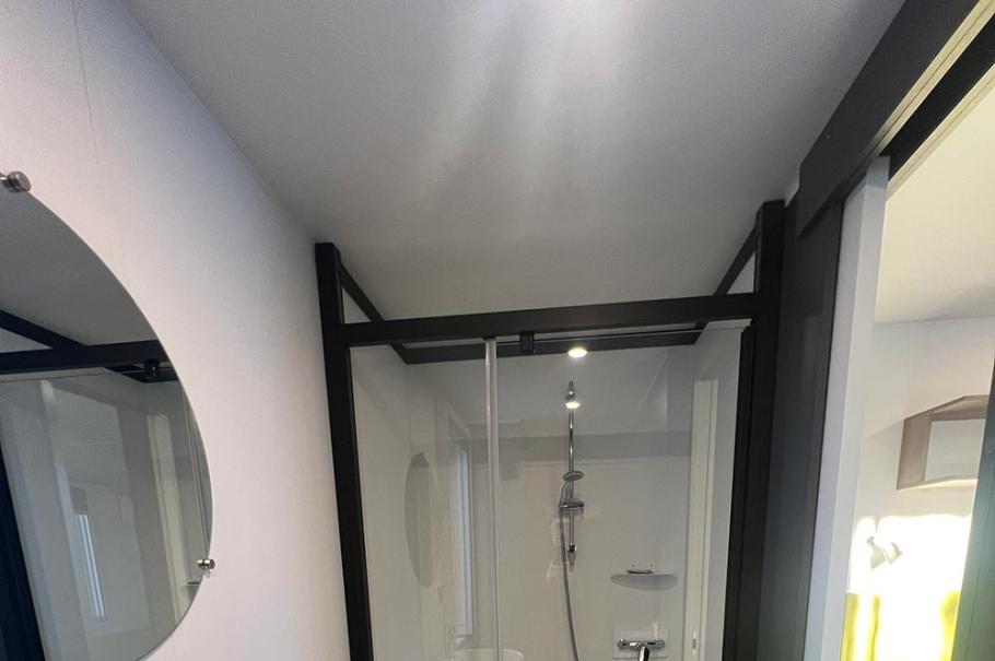 Bagno moderno con doccia in vetro, lavandino ovale e specchio rotondo.