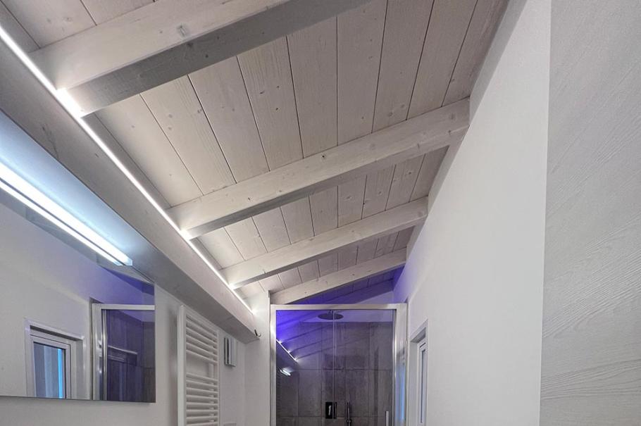 Bagno moderno con doccia, soffitto in legno e pavimento in parquet.