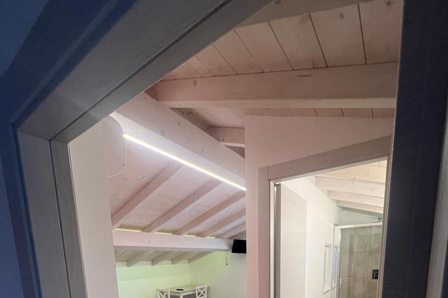 Camera mansardata con letto, pavimento in legno e bagno privato.