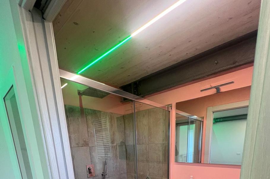 Bagno moderno con doccia in vetro, lavandino sospeso e illuminazione LED.